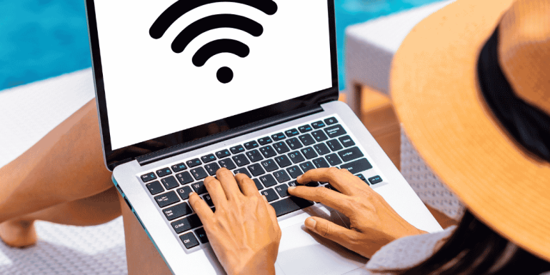 Henkilö käyttää avointa WiFi-verkkoa kannettavalla tietokoneella lomalla uima-altaan äärellä